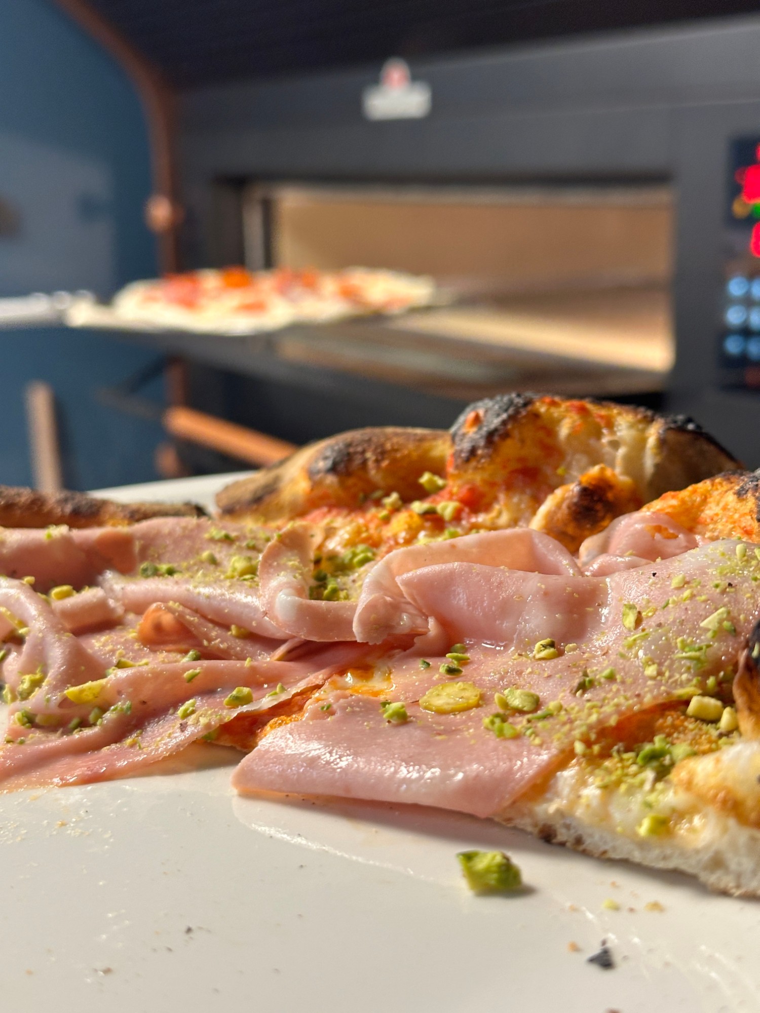 Nybakt pizza med skinke og pistasj rett fra ovnen hos Molo
